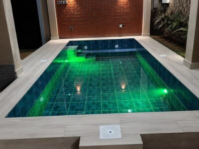 Piscine couverte avec éclairage LED vert et margelles effet bois